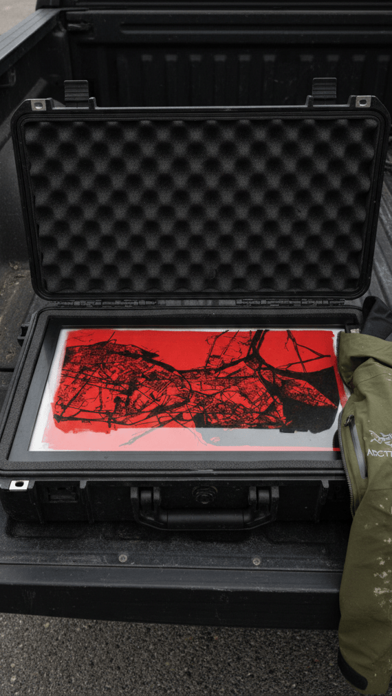 Original pen plotter artwork in a black hard-shell protective travel case — red and black generative art with collector-grade packaging for safe shipping.