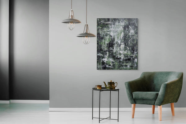 a modern living room with a green armchair, a small side table with a teapot and cups, and two hanging pendant lights. The room has a neutral color scheme with gray walls and a white floor, creating a calm and inviting atmosphere.