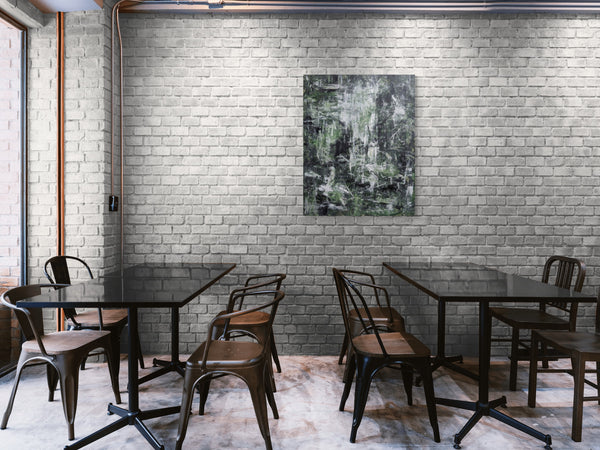 a modern, minimalist dining or meeting space with a brick wall backdrop, wooden tables and chairs, and a large abstract painting hanging on the wall.