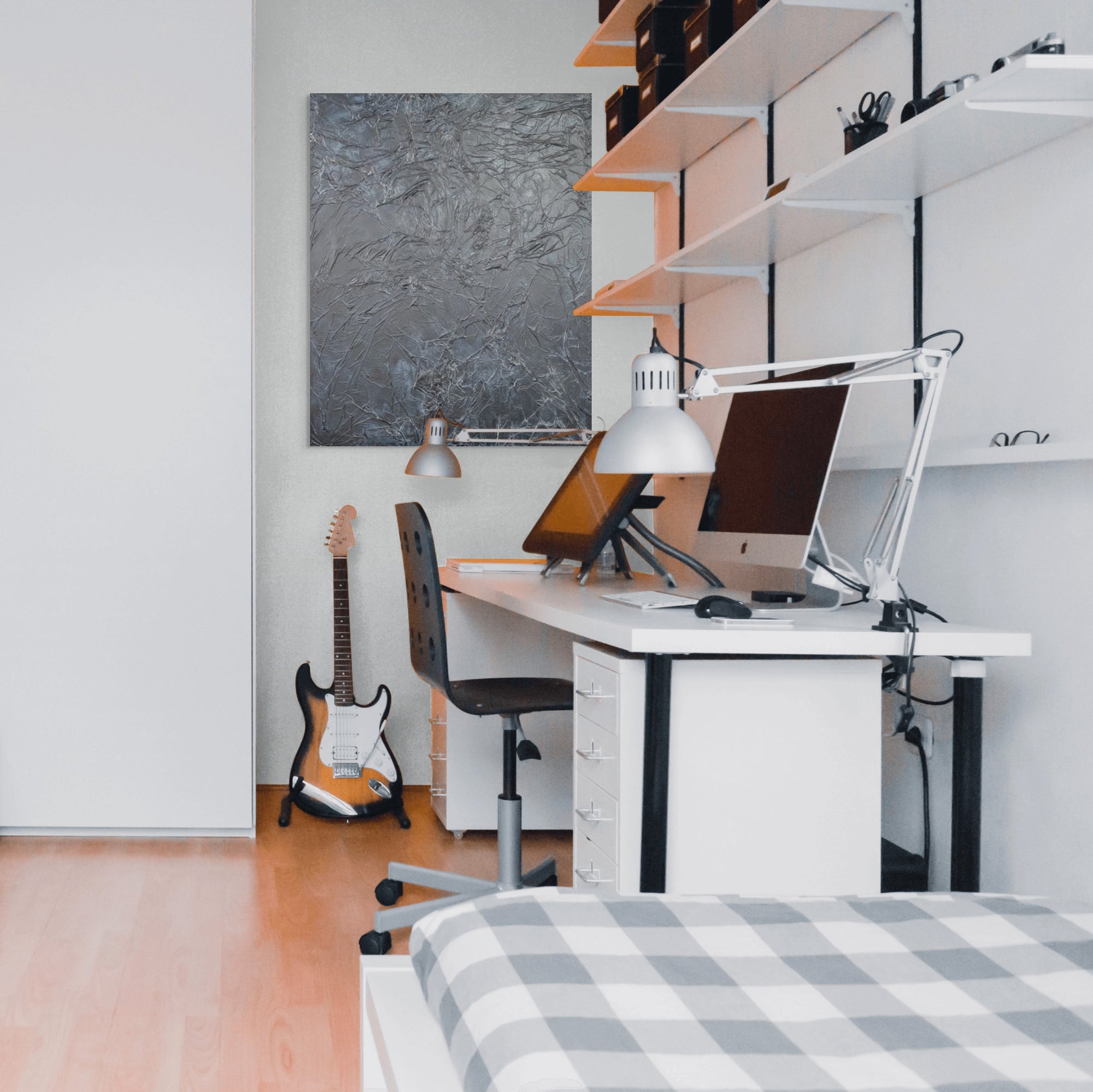 a modern, minimalist bedroom with a white desk, a guitar, and a bed.
